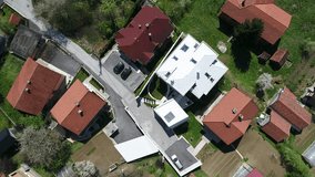 Aerial video view of a child standing on the grass in front his home yard