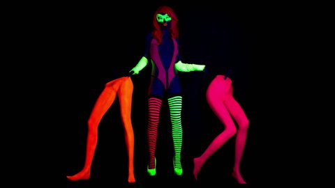 4k fantastic video of sexy cyber raver woman filmed in fluorescent clothing under UV black light. 2 mannequin legs stand either side of her