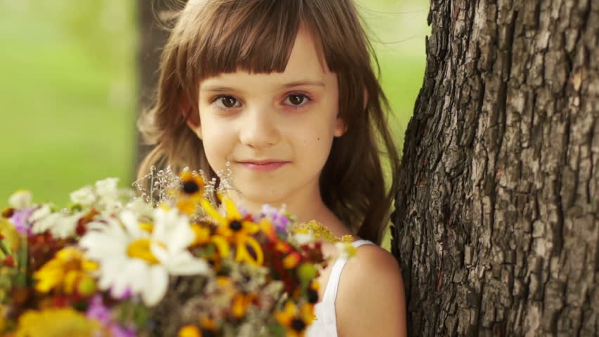 Closeup portrait of a girl with a bouquet of flowers near the tree
