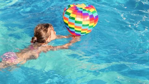 boy and girl swim in pool with inflatable multi-colored toys