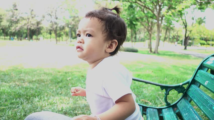 Asian baby girl playing on bench in park
