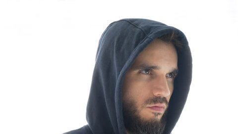 Close-up of serious thoughtful bearded man face in hoodie looking at you, studio isolated on white background.