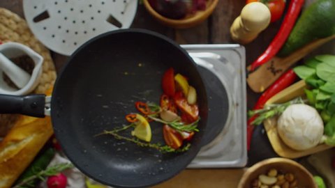 Top view of male hand holding frying pan and tossing up mixed vegetables in slow motion Stock Video