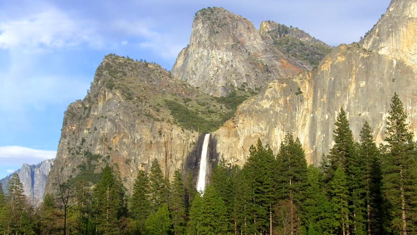 A wide shot of Sentinel Falls, granite mountains and pine tree forest in