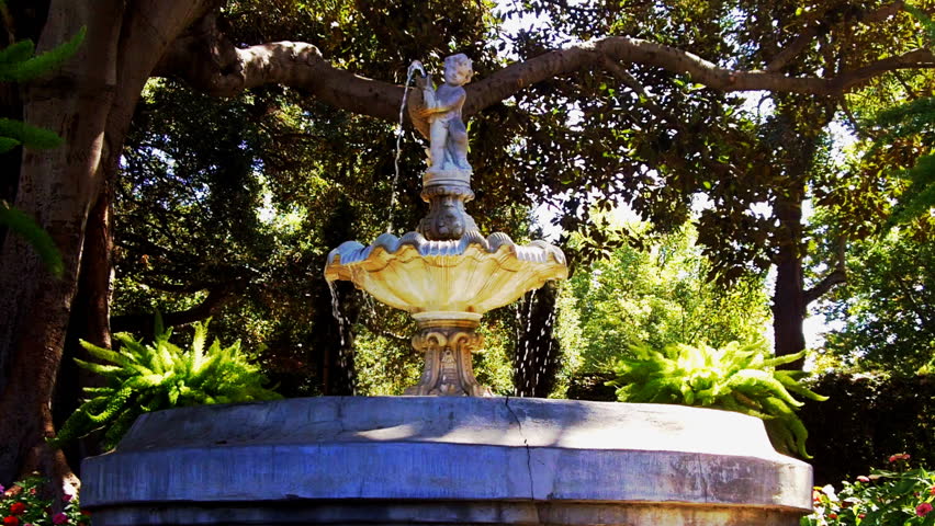 An old styled tiered fountain with a cherub pouring water in a Victorian era