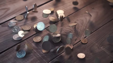 Pile of coins falling on the wooden table. Economic and financial crisis. Salary fall and pension increase, heap or bunch funds for buy for people. Close up of capital indoors. Studio slow motion