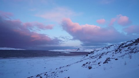 Storm big waves winter north polar arctic rock mountain coast. Dramatic cinematic clouds at horizon. Deep blue color. Snow blizzard wind. Timelapse sunset