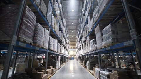 Warehouses large logistics commerce structure with boxes on the shelf. Teamwork male person industry production, using machine work and vehicle, delivering merchandise for transnational export indoors