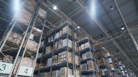 Camera shot of different materials in stockroom: racks indoor around: boxes, pallets, inventory, products, containers, merchandises. Logistics large place with transnational stuff to shipment process