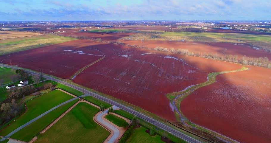 Cloud shadows and sunlight drift across wet Springtime fields of Wisconsin, aerial time lapse view.