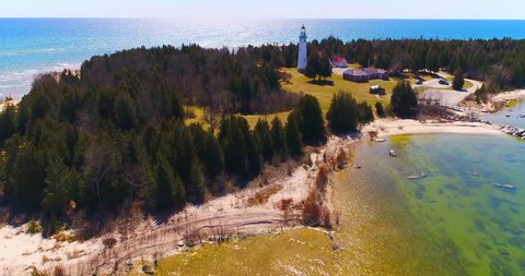 Scenic Lighthouse stands tall on rocky peninsula, breathtaking aerial view.
