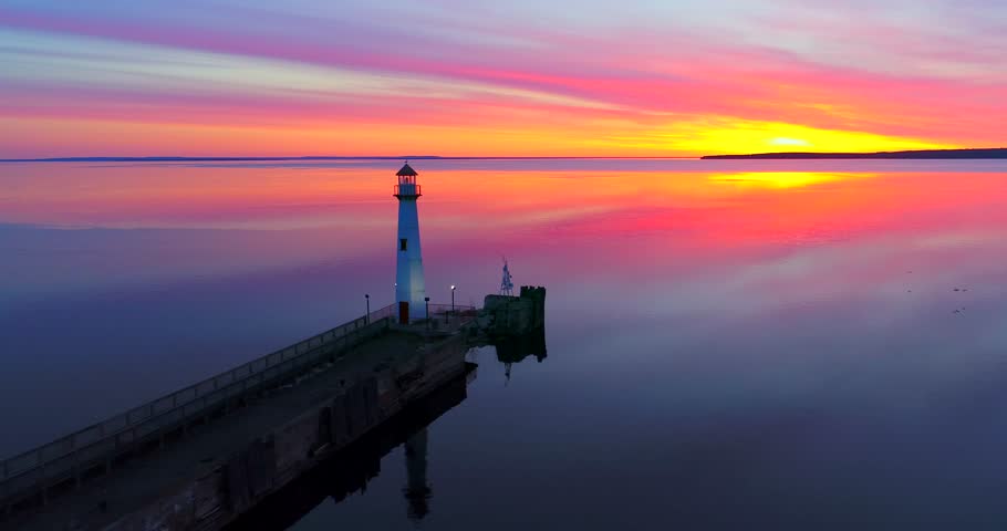 Majestic Lighthouse greets the light of dawn, Saint Ignace, Upper Michigan. Scenic aerial flyby. Mackinac Island can be seen in the distance.