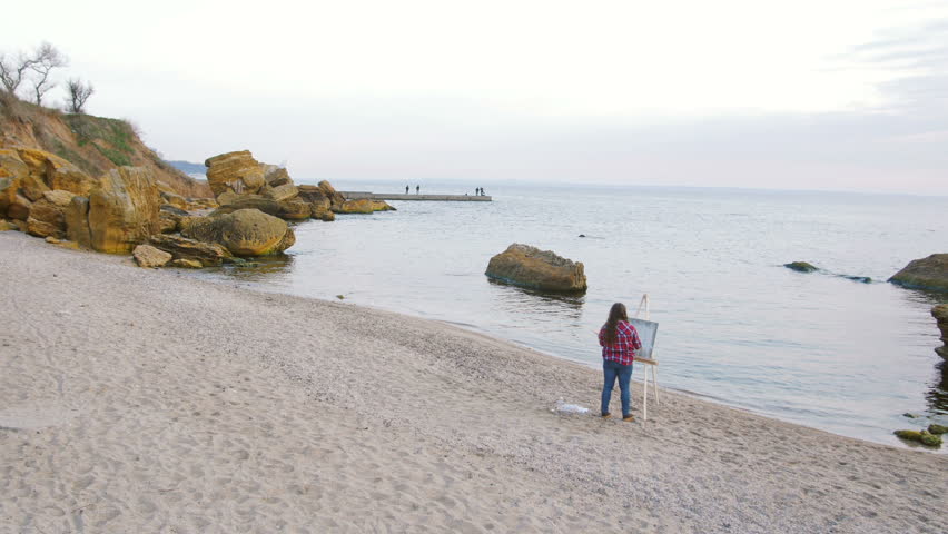 Female artist painting an sea landscape