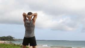 Dumbbell fitness exercises. Man training Dumbbell Triceps Extension exercise. AKA Standing Dumbbell Tricep Extension. Fit male fitness model workout on beach.