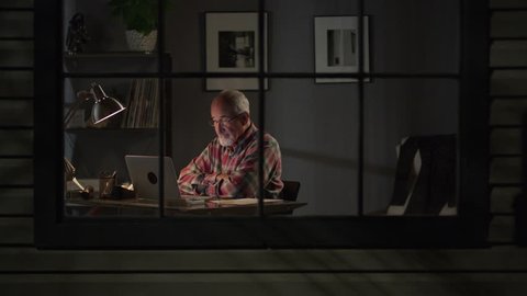 Medium zoom in shot of older man video chatting on laptop / Cedar Hills, Utah, United States