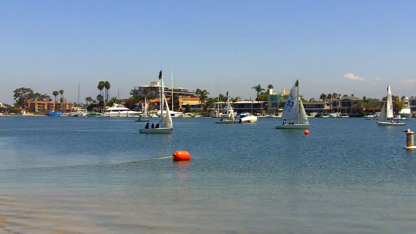Children sail little sailboats on the calm blue waters of Alamitos Bay in Long