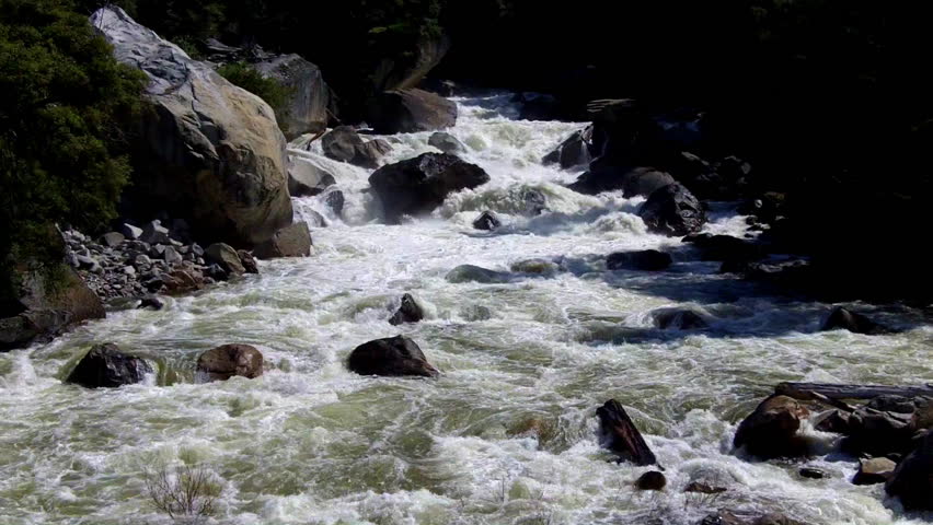 Whitewater rapids foam and cascade on the swollen with snow-melt Merced River in