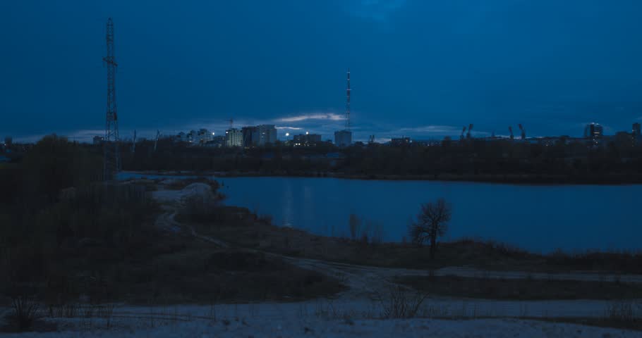 Blue hour on the river with tiny building on horizon. Timelapse
