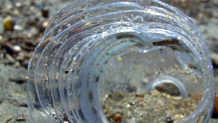 An extreme close up with shallow focus of plastic bottle trash on the beach in