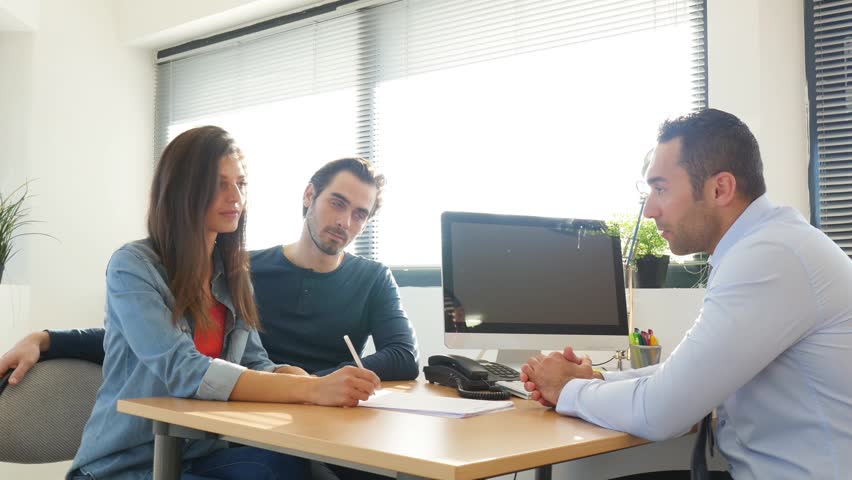 Buying agreement contract signature and hand shaking between young couple and professional finance business man in office  | Shutterstock HD Video #25972235