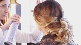 Hair stylist creating hairstyle for a brunette woman