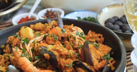 Dolly revealing view of a Spanish seafood paella: mussels, king prawns, langoustine, haddock