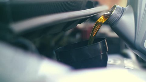 Pouring fresh new clean synthetic oil into car's engine, closeup. 4K UHD slow, motion.