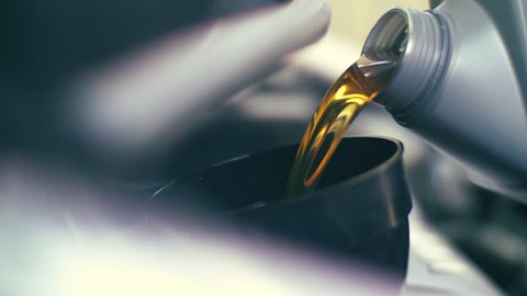 Pouring fresh new clean synthetic oil into car's engine, closeup. 4K UHD slow, motion.