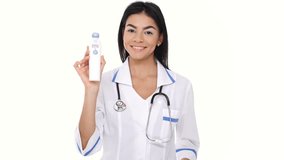 Smiling young woman nurse showing device for measuring temperature and gesture  thumb up isolated