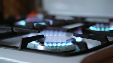 Natural gas inflammation in stove burner. Stove top burner turns on. Turns on gas stove burners. Blue gas. Stove top burner igniting into a blue cooking flame.