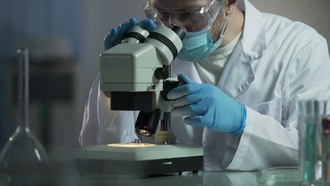 Scientists working in labs on cure that would help stop AIDS spreading. Chemical expert looking at analysis through microscope, developing new medication, experiment. Chemist examining blood cells
