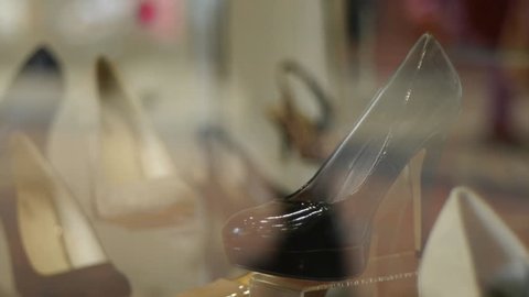 Part of a shop window shoe display. People walking past are reflected in the glass. The display is sharp. The people are blurred.