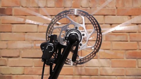 Spinning bicycle wheel against a brick wall in the background.