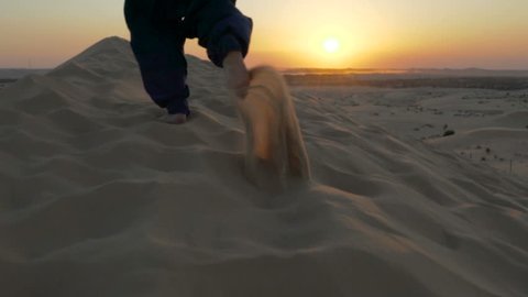  running up a hill sand dune in desert. running in sand dune in desert. two bare feet running in the sand
