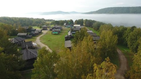 Taltsy Museum Wooden Architecture and Ethnography. Angara river Russia Siberia.  Savior's gate tower ostrog reconstruction. Morning fog sunrise spring summer forest. Aerial drone descent to street