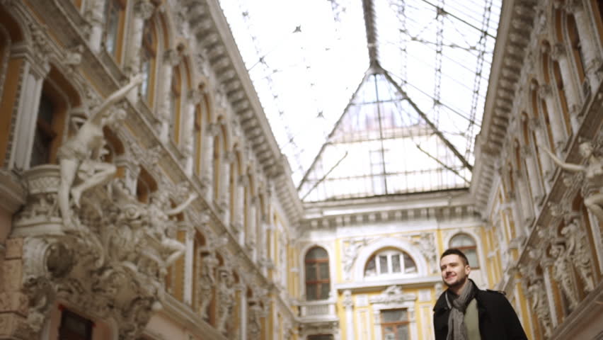 Confident young handsome Caucasian male walking through great beautiful passageway in Odessa in slowmotion