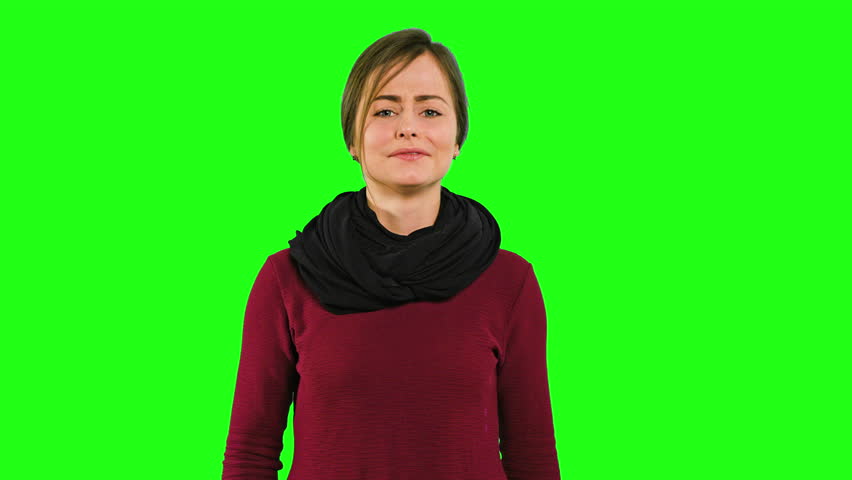 A young lady shaking her head in fury and crying against a green background. Medium shot