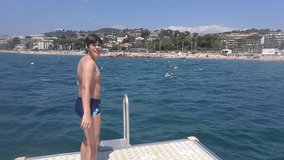 Boy jump with turning from platform in Mediterranean Sea near seaside of Cannes, mobile phone video.
