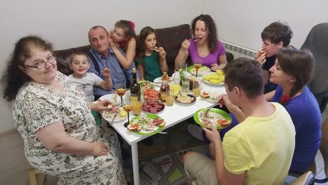 Big family from nine people adults and children sit at table eat and drink at home, mobile phone video.