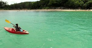 Video from drone. Beautiful young girl floating on a kayak in a beautiful bay on a sunny day. The girl crosses the bay using the kayak. Nai Harn beach, Thailand 2017.