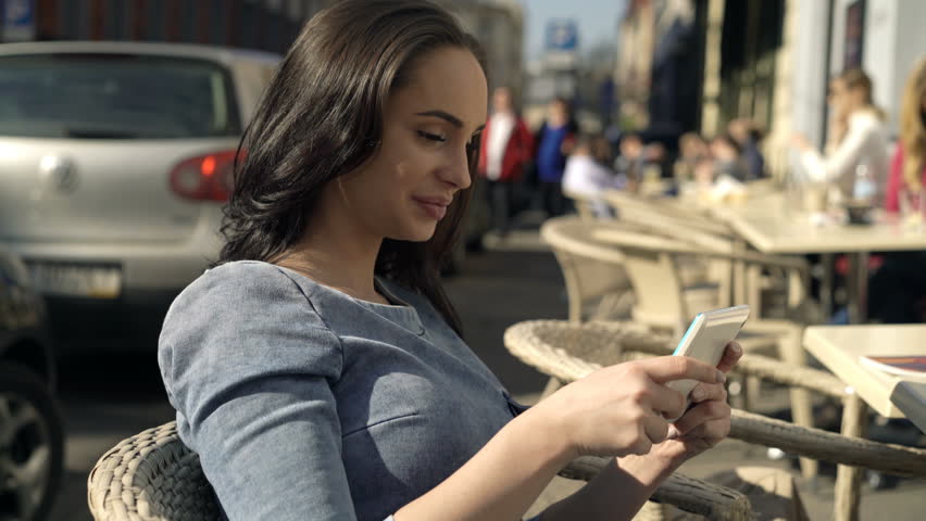 Portrait of happy, pretty woman with tablet sitting in cafe in city
