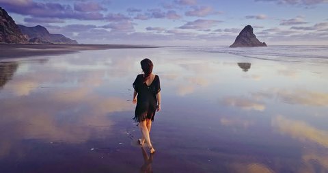 Aerial Of woman walking and running on a beach, karekare, Auckland, New Zealand