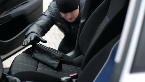 Crime concept, criminal thief stealing bag from parked car. Close up
