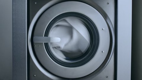 Industrial washer machine working. Clothes laundry machine. Close up of laundry clothes in industry washing machine. Working washing machine. Closeup of clothes washer. Laundry clothes washing