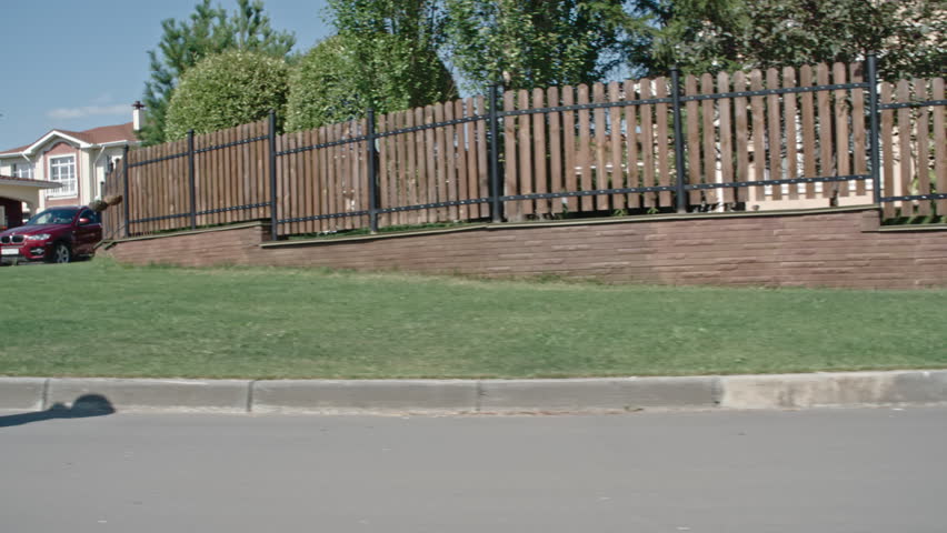 Medium shot tilt up tracking shot of active senior man learning to skateboard down town road