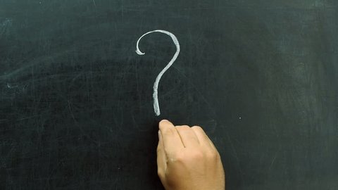 Hand writing question mark with chalk on blackboard or chalkboard