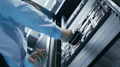 Long Angle Shot In Fully Working Data Center IT Engineer Installs Hard Drive into Server Rack. Detailed and Technically Accurate Footage. Shot on RED EPIC-W 8K Helium Cinema Camera.
