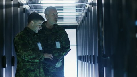In Data Center Two Military Men Work with Open Server Rack Cabinet. One Holds Military Edition Laptop. Shot on RED EPIC-W 8K Helium Cinema Camera.