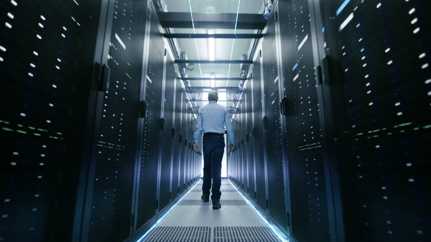 Server Engineer Walks into Opening Sliding Doors and Goes Through Data Center Corridor. Working Server Racks Blink with LED Lights. Shot on RED EPIC-W 8K Helium Cinema Camera.