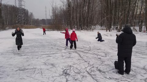Family of six skate and throw snowballs on pond in park Losiny Ostrov, mobile phone video.